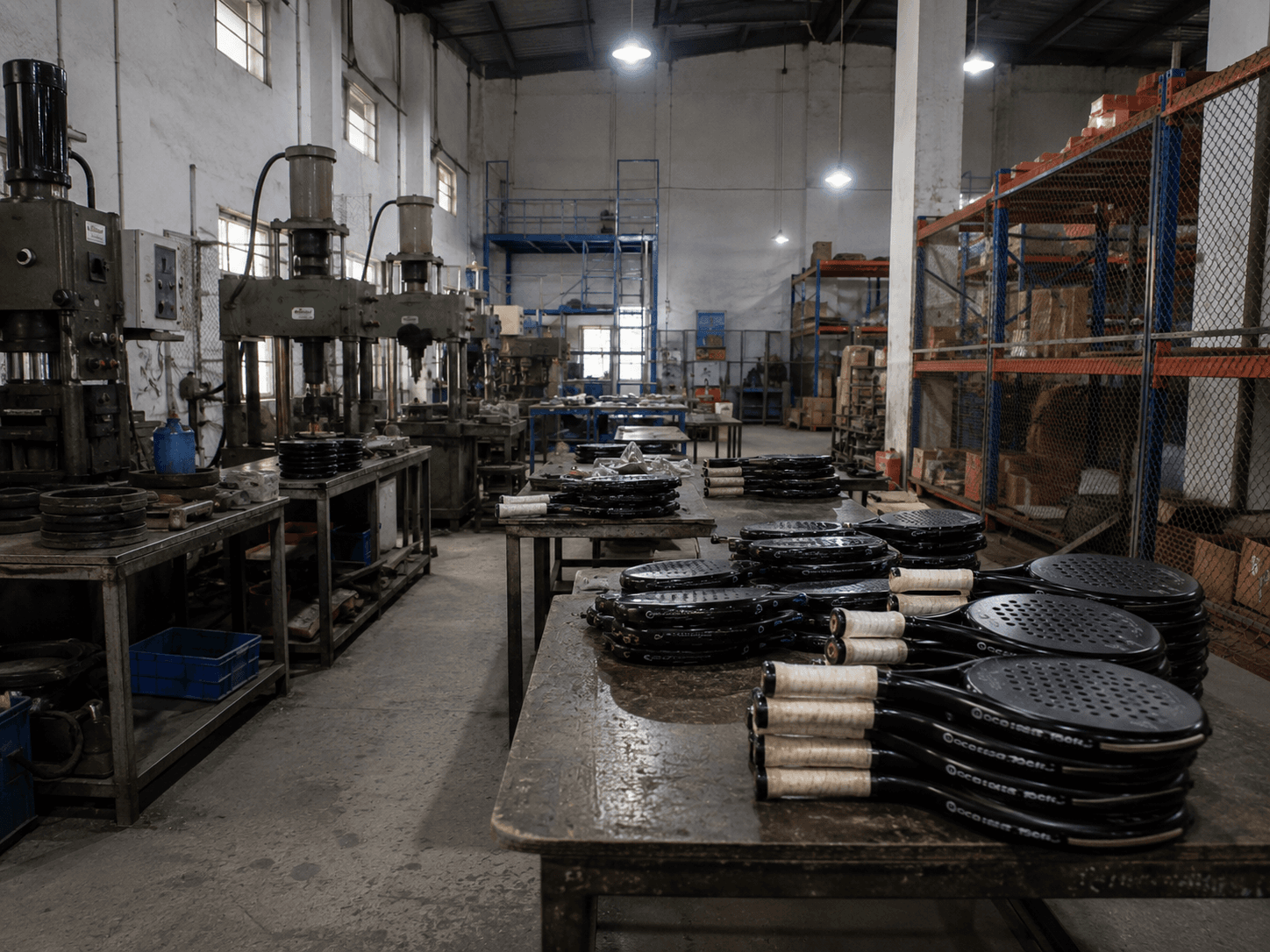 Factory floor with hydraulic presses and finished rackets staged for the next stage of production